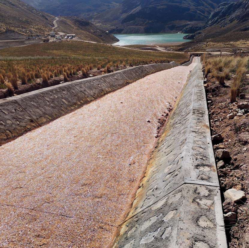 Canal de concreto en zona altoandina con laguna al fondo